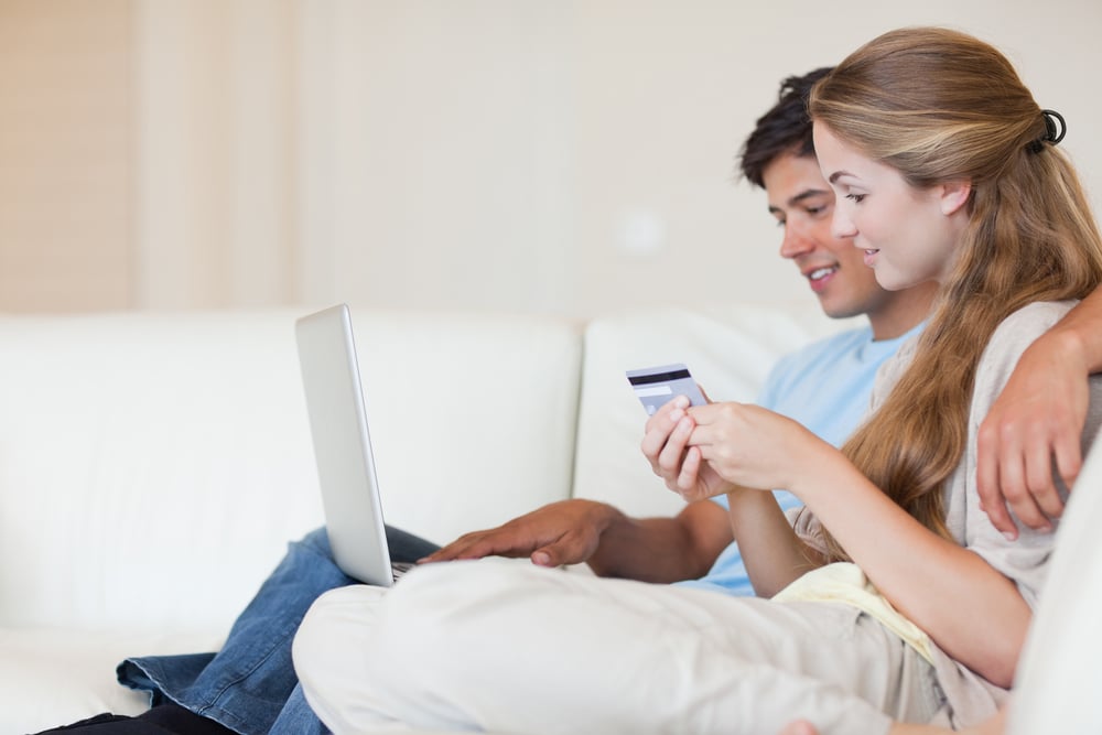 man and woman looking at laptop holding credit card